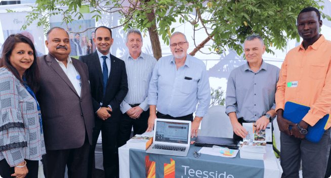 A group of people consisting of counsellors, university delegates, and financial advisors posing happily at an exhibition.